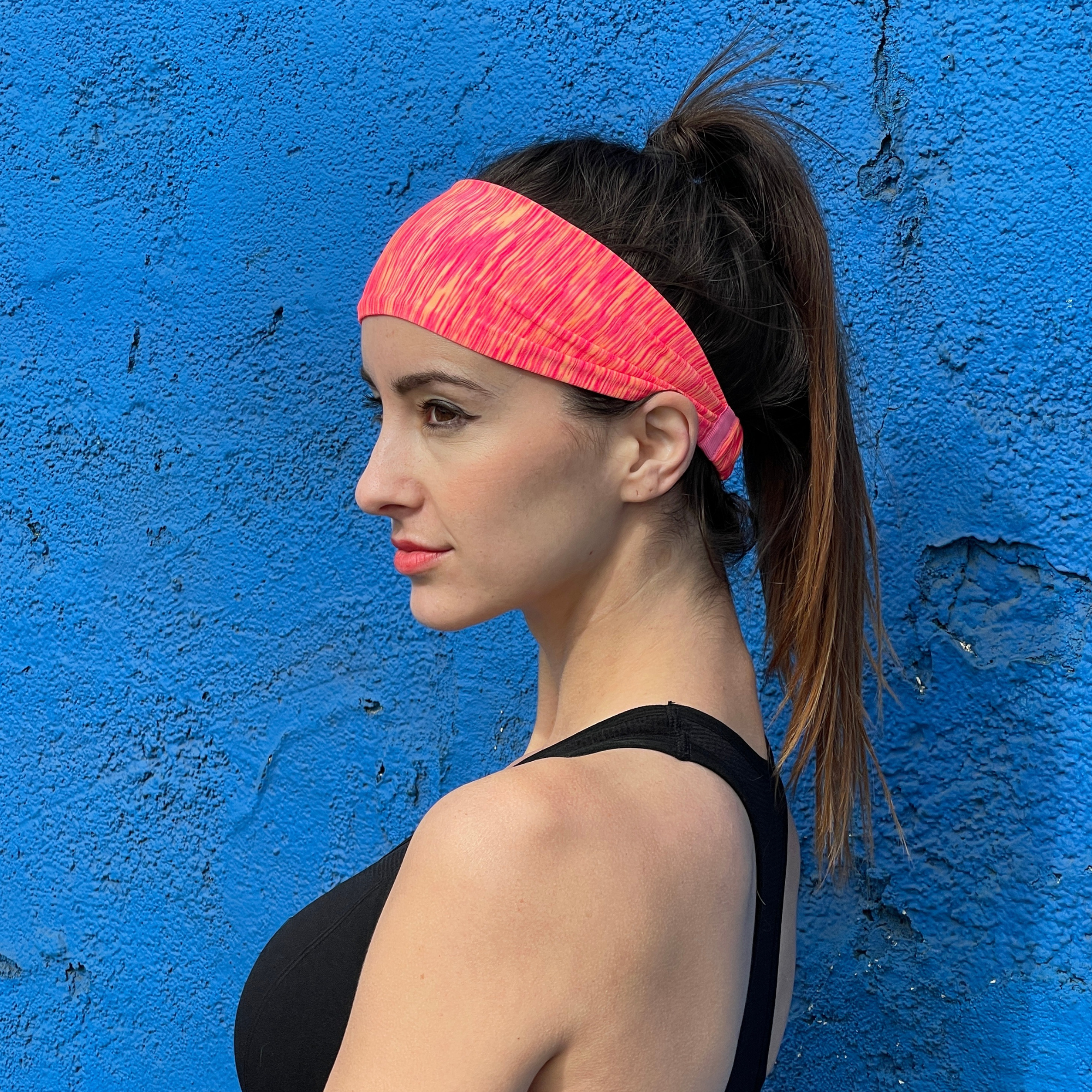 Woman wearing a pink headband against a blue wall