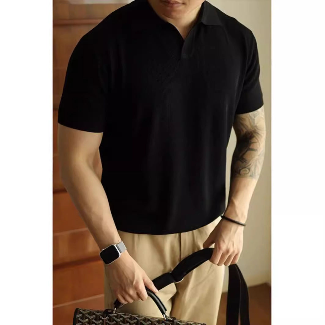 Man wearing a black polo shirt and beige pants holding a bag indoors.
