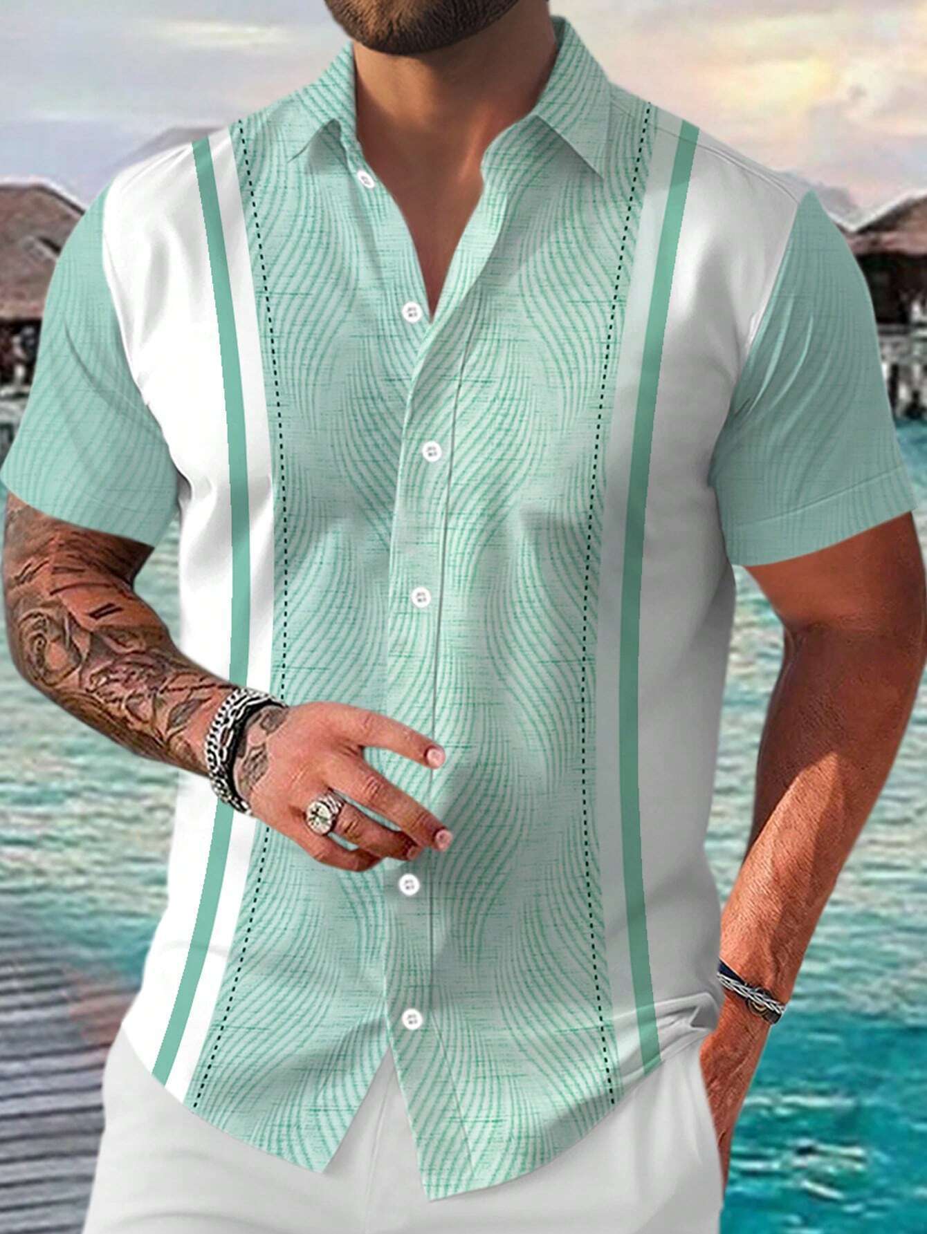 Man wearing a light green and white patterned shirt with a blurred beach background