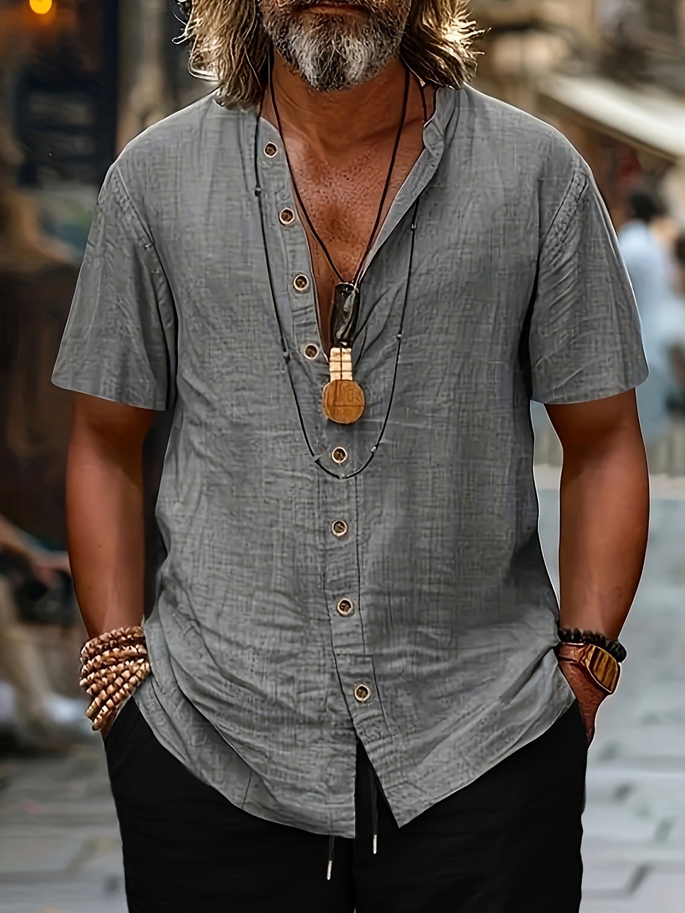 Man wearing a gray short-sleeve shirt with a necklace, standing on a street.