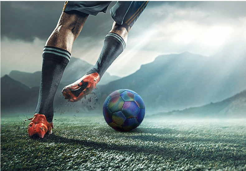 Person kicking a soccer ball on a grassy field with mountains in the background