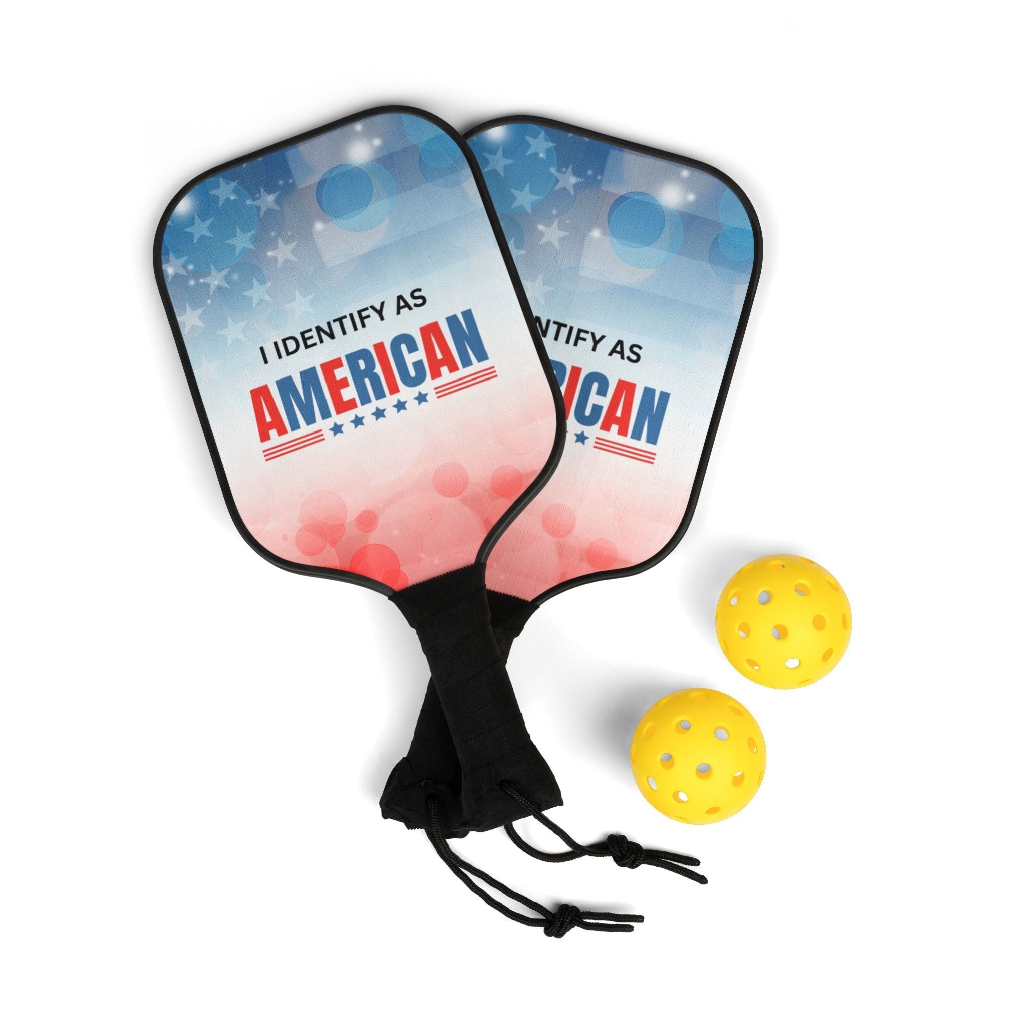Two pickleball paddles with 'I Identify as American' text and two yellow pickleballs on a white background.